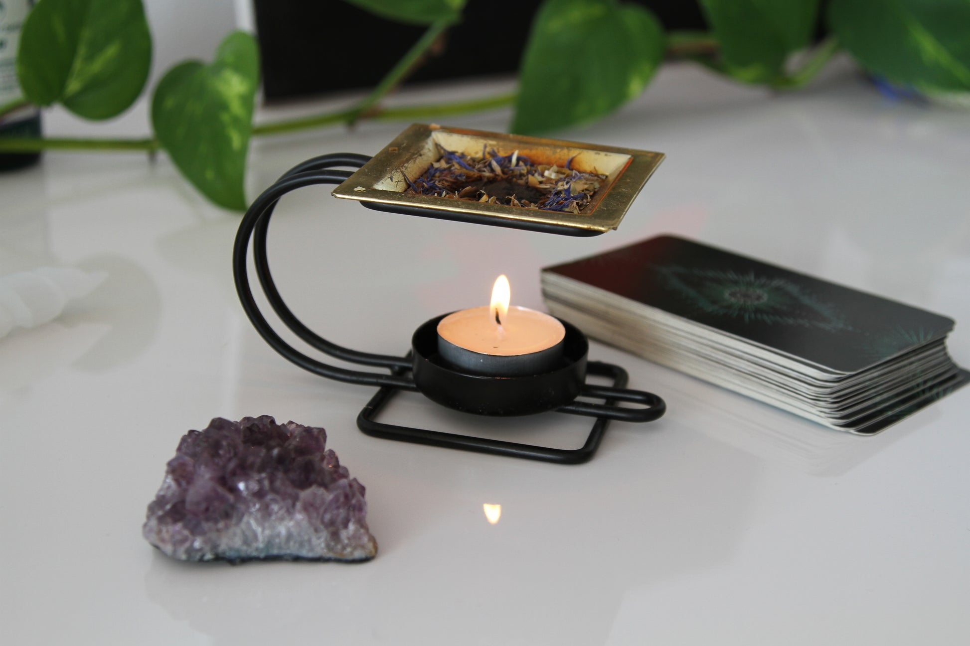 A lit candle illuminating a tarot deck and amethyst crystal, creating a tranquil and mystical ambiance for spiritual exploration.