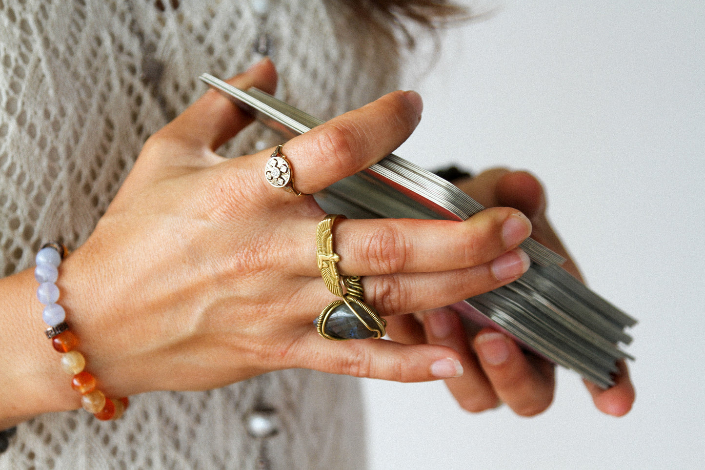 Close-up of Ira shuffling tarot cards, highlighting her beautiful rings and bracelet, radiating a sense of style and spiritual elegance.